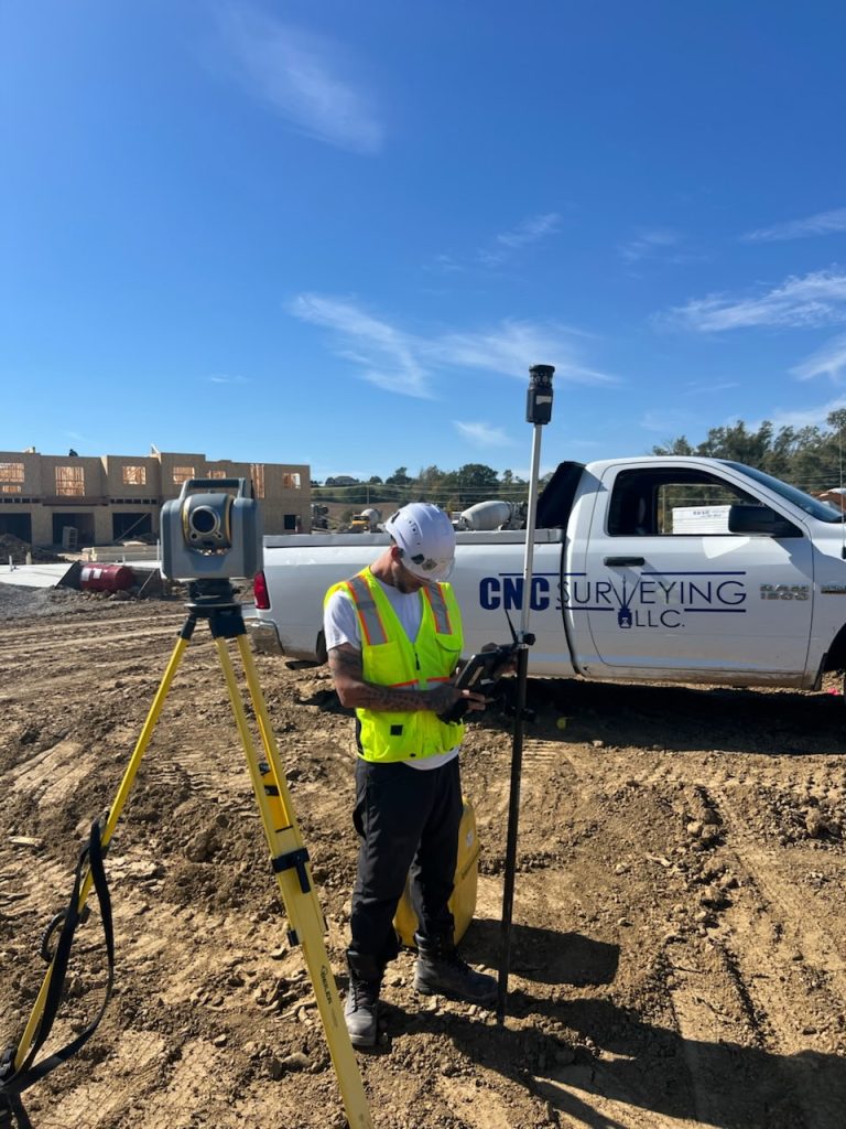 surveyor on construction site using Trimble 3D Scanner to collect and layout points of surveying and staking