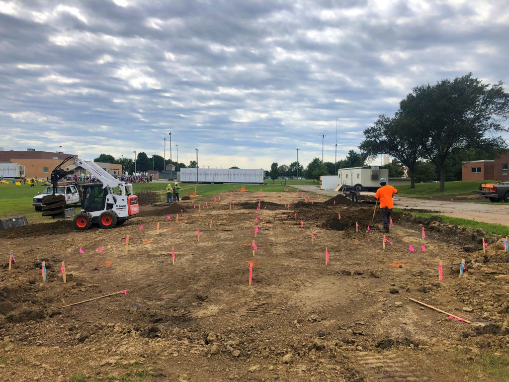 dirt graded on construction site marked with surveyors stakes to show paving contractor the location and elevation of curbs to form.