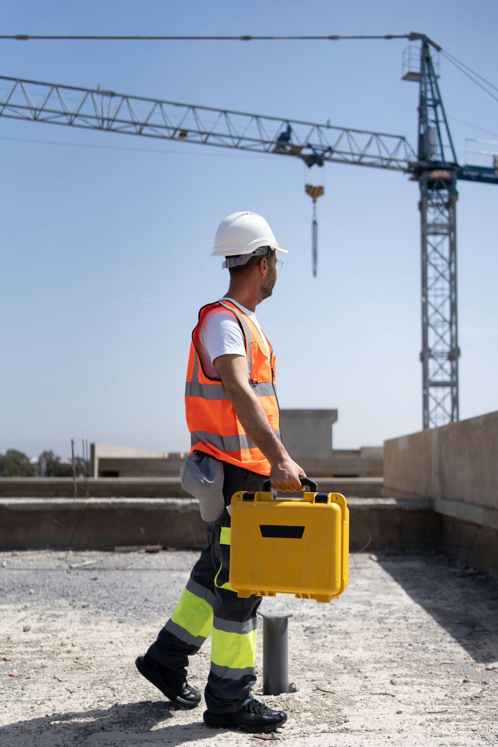 surveyor on a construction site with a crane in background